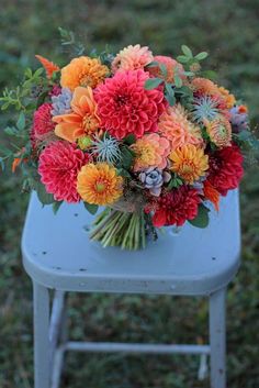 a bouquet of colorful flowers sitting on top of a blue chair in the middle of grass