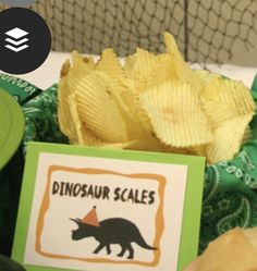 there is a plate with chips and a card on it that says dinosaur scales next to some other items