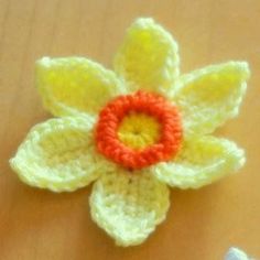 a crocheted flower sitting on top of a wooden table