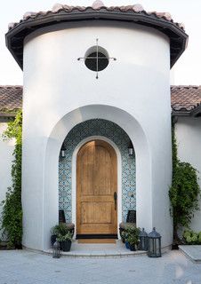 a white building with a wooden door and two planters