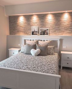 a white bed with pillows and two pictures on the wall above it's headboard