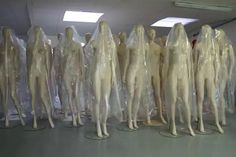 several mannequins are lined up in plastic bags