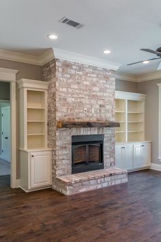 an empty living room with a brick fireplace