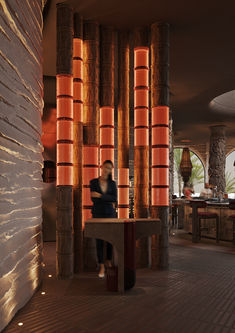 a person sitting on a bench in front of some tall orange columns with lights behind them