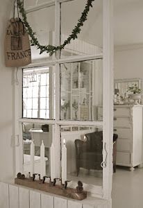 an old window is decorated with greenery and candles for the holiday season in this white living room