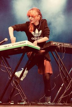 a woman sitting at a keyboard on top of a stage