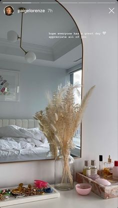 a mirror sitting on top of a white counter next to a vase filled with flowers