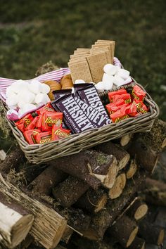 a basket filled with marshmallows sitting on top of a pile of logs