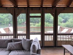 a living room filled with furniture and lots of windows overlooking a lake in the background