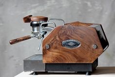 an espresso machine sitting on top of a wooden table next to a wall