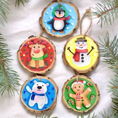 four christmas ornaments are hanging from a pine tree with snowmen and bears on them