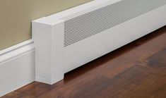 a white radiator on the floor next to a wall and wood flooring