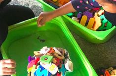 two children playing with toys in green trays