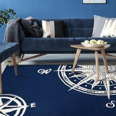 a living room with blue walls and white furniture on the floor, along with a rug that has an image of a compass