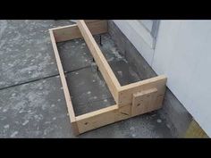 a wooden bench sitting on top of a cement floor next to a building with windows