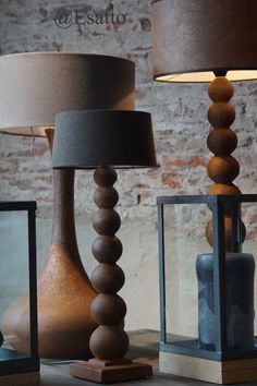 three wooden lamps sitting next to each other on top of a table with a brick wall in the background