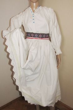 "Very old folk costume consisting of two pieces: skirt and folk shirt. Both are handmade and have handmade embroidery. The shirt is with embroidery on the shoulders, typical of the Arad region. It has fine embroidery on the sleeve, shoulders and cuffs made of beige thread. The neck has blue stitches. The shirt has old blue glass buttons. The cuffs end with laces. Fits S-M measures. Although I added more cloth under the arm to make it wider and more comfortable to wear, the shirt still has a smal Traditional Embroidered Peasant Dress, Traditional White Costume Dress, White Cotton Peasant Prairie Dress, White Peasant Dress For Daywear, Traditional Cotton Costume Dress, Peasant Outfit, Fine Embroidery, Handmade Costumes, Traditional Costume