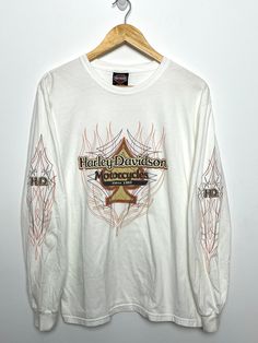 This tee shirt shows discoloration along the bottom side of both sleeves and on the upper right shoulder. Measurements Pit to pit: 20 inches Top to bottom: 27 1/2 inches Acid Wash Long Sleeve T-shirt With Graphic Print, Acid Wash Long Sleeve Streetwear Top, Distressed Long Sleeve Tops For Streetwear, Acid Wash Long Sleeve Tops For Streetwear, Acid Wash Long Sleeve T-shirt With Letter Print, Vintage White Long Sleeve T-shirt, Bleached Crew Neck Top For Streetwear, Fall Streetwear Bleached Tops, White Bleached Long Sleeve Top