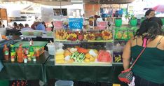 a woman standing in front of a table filled with lots of fruits and juices