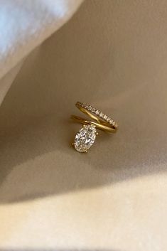 two diamond rings sitting on top of a white cloth covered in light colored fabric,