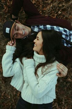 a young man and woman laying on the ground next to each other with their arms around each other