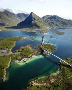 an aerial view of a bridge over water with mountains in the background