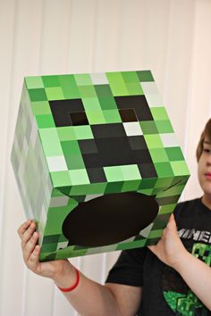 a young boy holding up a box made to look like an creeper