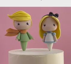 two small figurines on top of a white cake