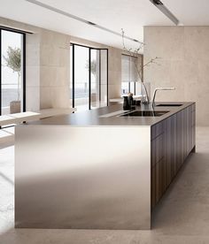 a modern kitchen with stainless steel counter tops and an island in front of large windows