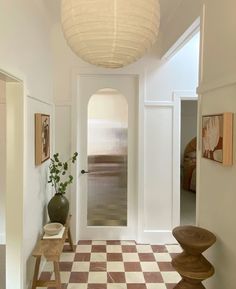 a hallway with checkered tile flooring and a round light fixture hanging from the ceiling