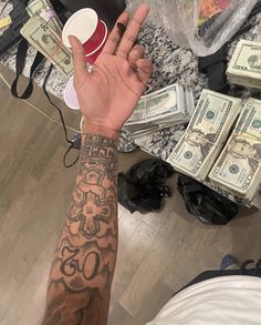 a man with tattoos on his arm holding up money