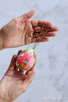 a person holding an ornament in their hand with the string attached to it