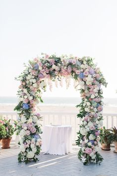 an outdoor ceremony setup with flowers and greenery on the side of the aisle, overlooking the ocean