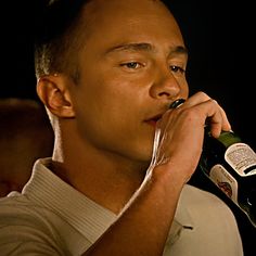 a man is drinking from a bottle while holding it to his mouth with both hands