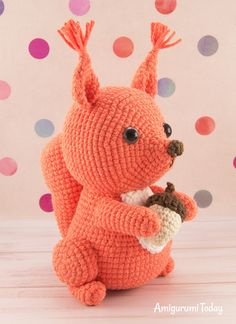 an orange crocheted stuffed animal holding a piece of food in it's paws