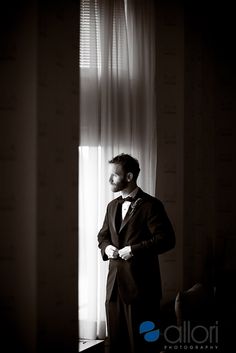 a man standing in front of a window wearing a suit