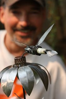 a man is holding a small metal object with scissors in it's hand and smiling at the camera