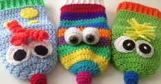 three crocheted little monster mittens with googly eyes and one wearing a hat