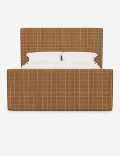 a bed with two pillows on top of it and a brown checkered upholstered headboard