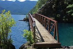 a wooden bridge over a body of water with mountains in the background