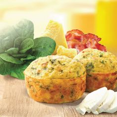 two muffins with spinach leaves, tomatoes and cheese on a wooden table