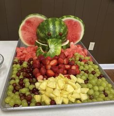 watermelon, grapes, strawberries and melon arranged on a tray