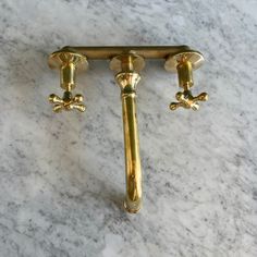 two golden handles on a white marble counter top with gold hardware and brass fittings