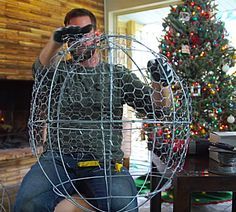 a man holding a camera in front of a christmas tree