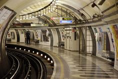 an empty subway station with people waiting for the train to come down it's tracks