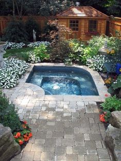 an outdoor hot tub surrounded by flowers and rocks