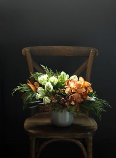 an arrangement of flowers is sitting on a chair