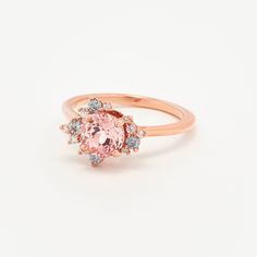 14K recycled gold Set in the center with a lovely 1.15ct (6mm) round cut lab grown rosé sapphire. With a blush hue reminiscent of the lovely color of morganite, our rosé sapphire features a slightly more saturated peachy-pink color, and offers a much better durability than morganite, making it ideal for an engagement ring! One of a kind asymmetrical cluster halo featuring sparkly colorless lab grown diamonds, peppered with moody grey moissanite, for a to-die-for salt and pepper halo! Truly a uni Pink Cluster Ring With Round Cut, Elegant Round Pink Sapphire Cluster Ring, Timeless Pink Rings With Center Stone, Rose Gold Morganite Round Cut Diamond Ring, Rose Gold Sapphire Ring For Proposal, Pink Cluster Ring With Center Stone, Morganite Sapphire Ring With Halo Setting, Brilliant Cut Pink Sapphire Diamond Ring In Rose Gold, Rose Gold Diamond Ring With Brilliant Cut Pink Sapphire