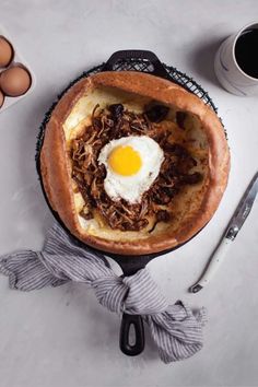 a pie with an egg in the middle on top of it next to some coffee