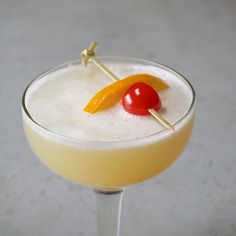 an alcoholic cocktail garnished with orange peels and a cherry on a stick